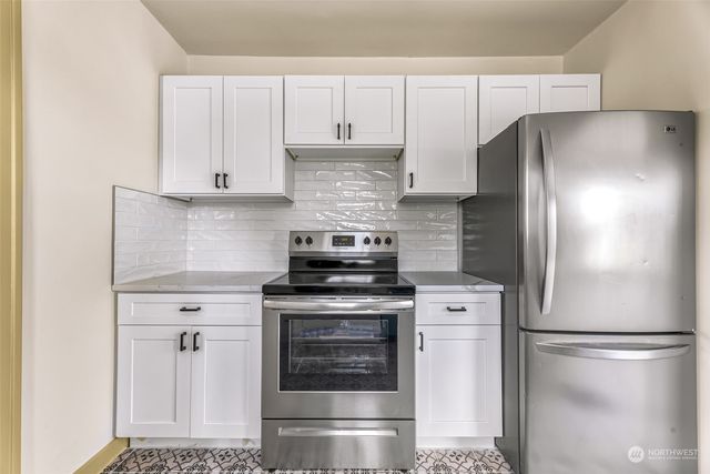 a kitchen with stainless steel appliances white cabinets and a refrigerator