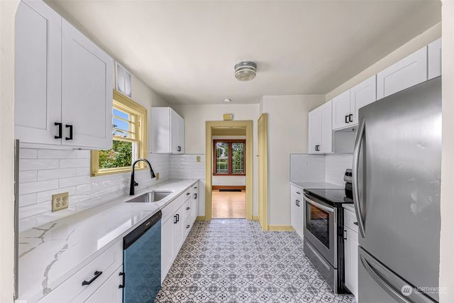 a kitchen with granite countertop a sink stove and refrigerator