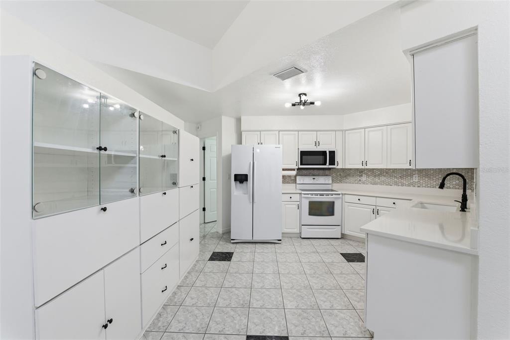 12515 Shadow Ridge Boulevard Hudson, FL 34669 - Photo 11 of 43 a kitchen with white cabinets and white appliances