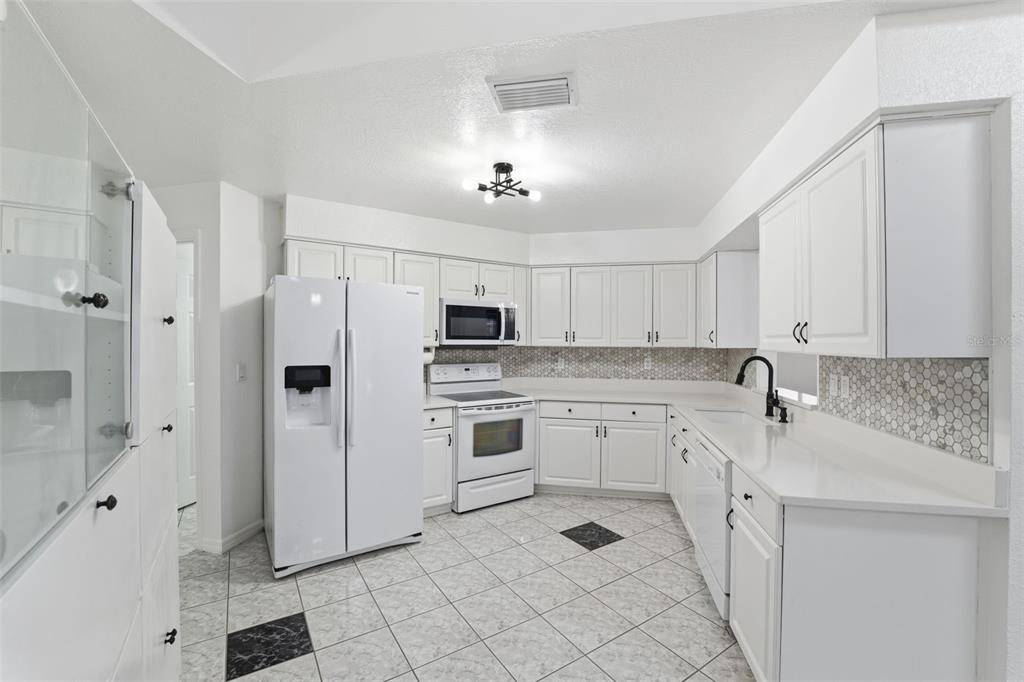 12515 Shadow Ridge Boulevard Hudson, FL 34669 - Photo 12 of 43 a kitchen with white cabinets and white appliances