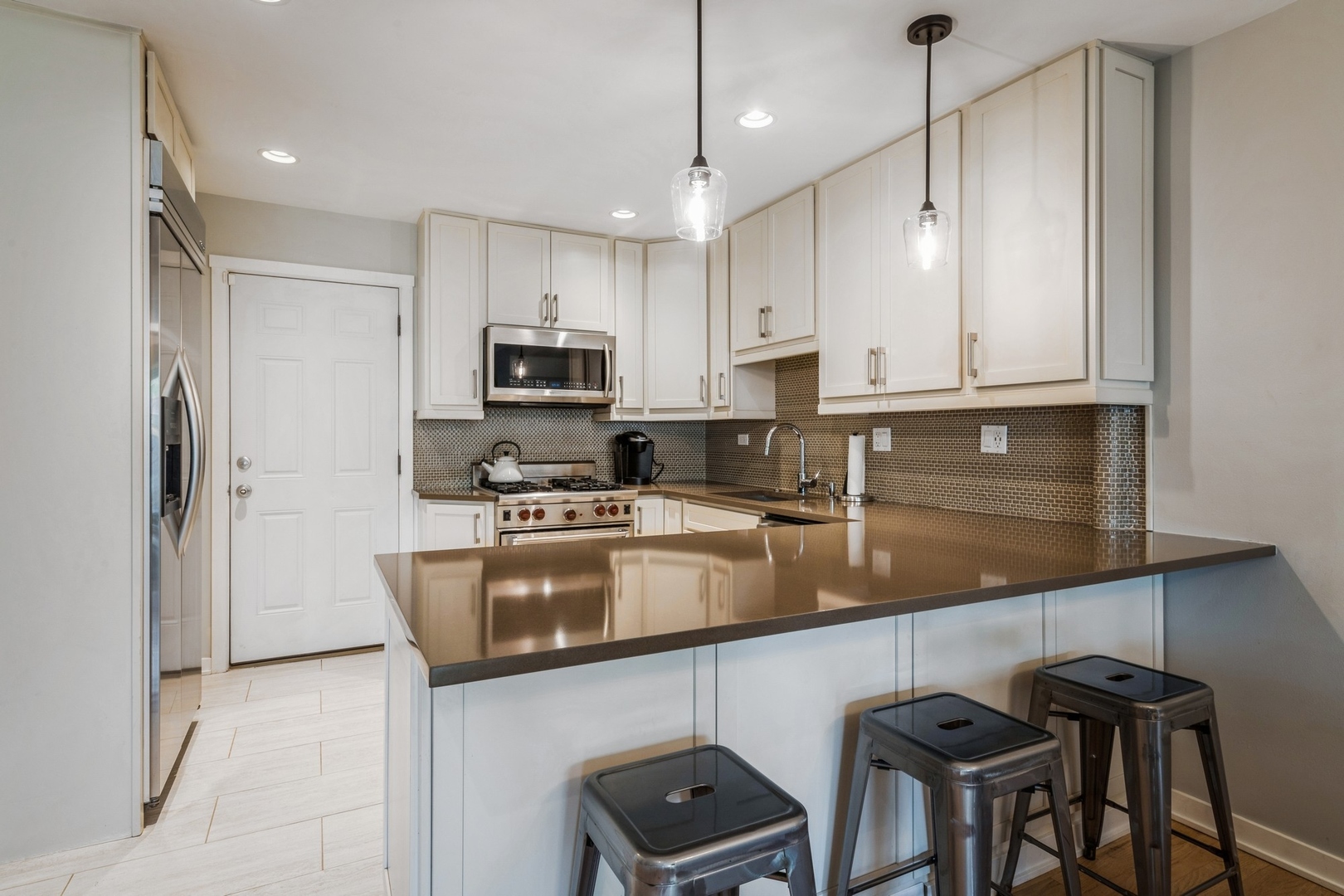 1063 Busse Highway Park Ridge, IL 60068 - Photo 6 of 16 a kitchen with stainless steel appliances granite countertop a stove a sink a microwave a refrigerator and white cabinets