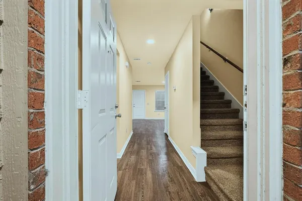 a view of a hallway with wooden floor and staircase