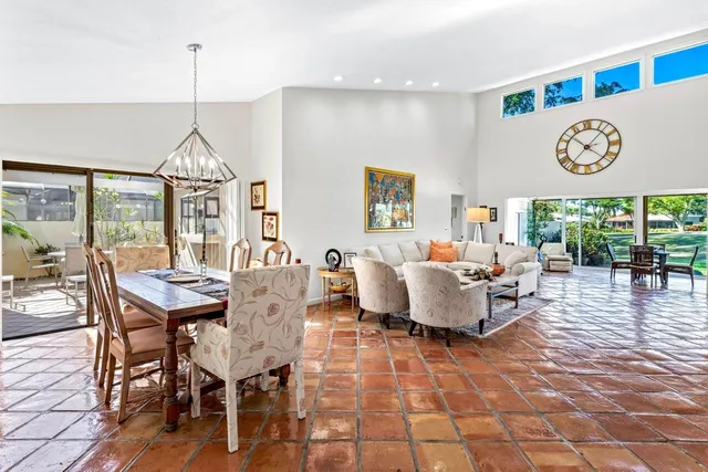 a living room with couch a dining table and a floor to ceiling window
