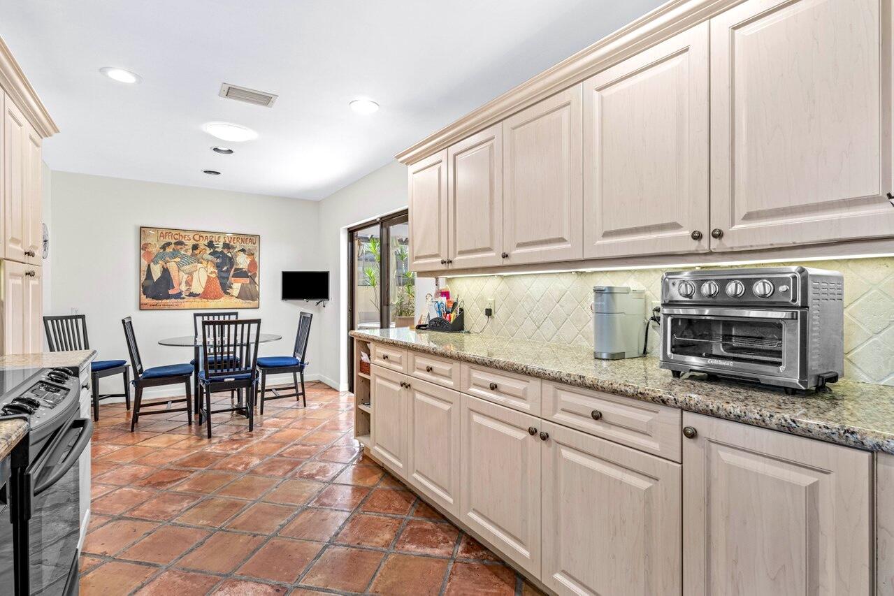19 Glens Drive West Boynton Beach, FL 33436 - Photo 20 of 69 a kitchen with stainless steel appliances granite countertop a stove top oven a sink a dining table and chairs with wooden floor