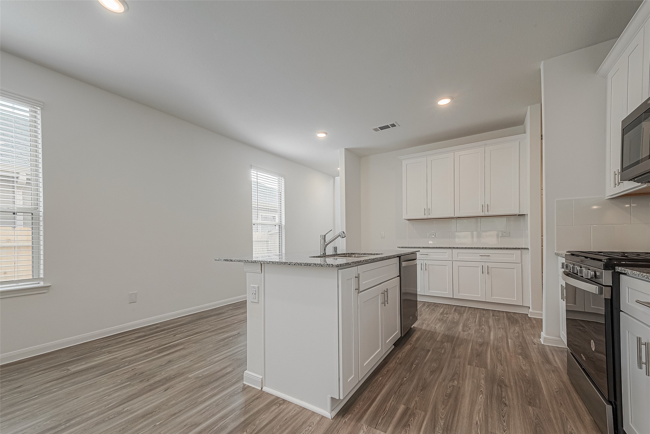 325 Maple Bark Trail Willis, TX 77378 - Photo 5 of 22 a kitchen with stainless steel appliances granite countertop a stove a sink and white cabinets with wooden floor