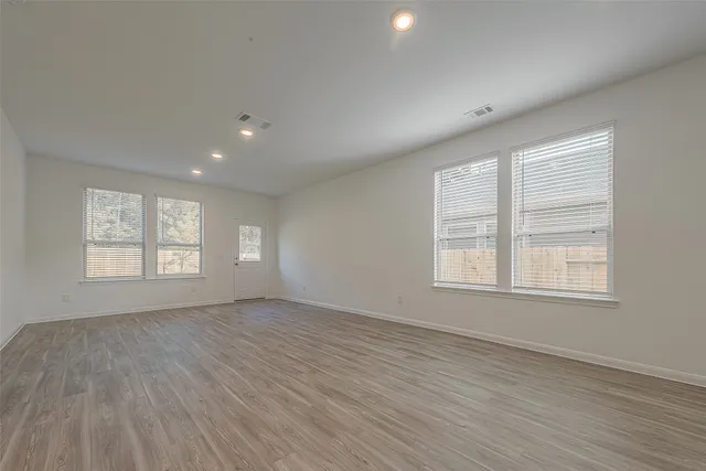 an empty room with wooden floor and windows