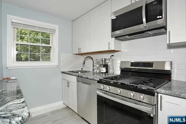 a kitchen with stainless steel appliances granite countertop a stove and a microwave