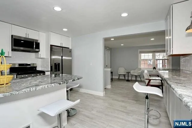 a kitchen with stainless steel appliances kitchen island granite countertop a sink and chairs