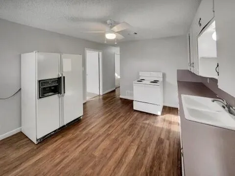 a kitchen with wooden floors and white appliances