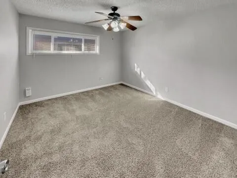 an empty room with a window and a ceiling fan