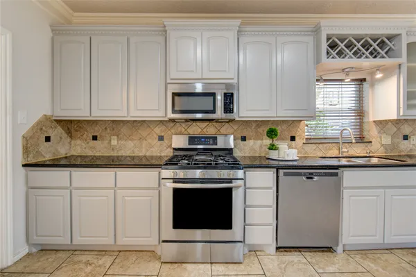 a kitchen with granite countertop white cabinets sink and stainless steel appliances