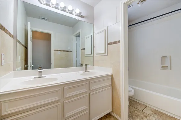 a bathroom with a sink double vanity granite tub and a mirror