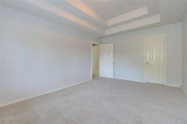 a view of an empty room and chandelier fan