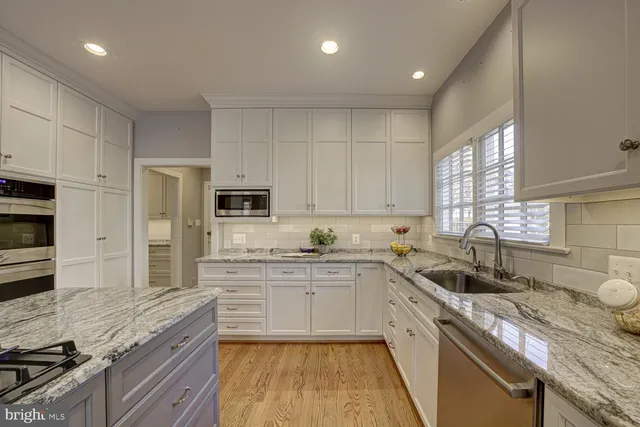 a kitchen with granite countertop a sink stainless steel appliances and cabinets