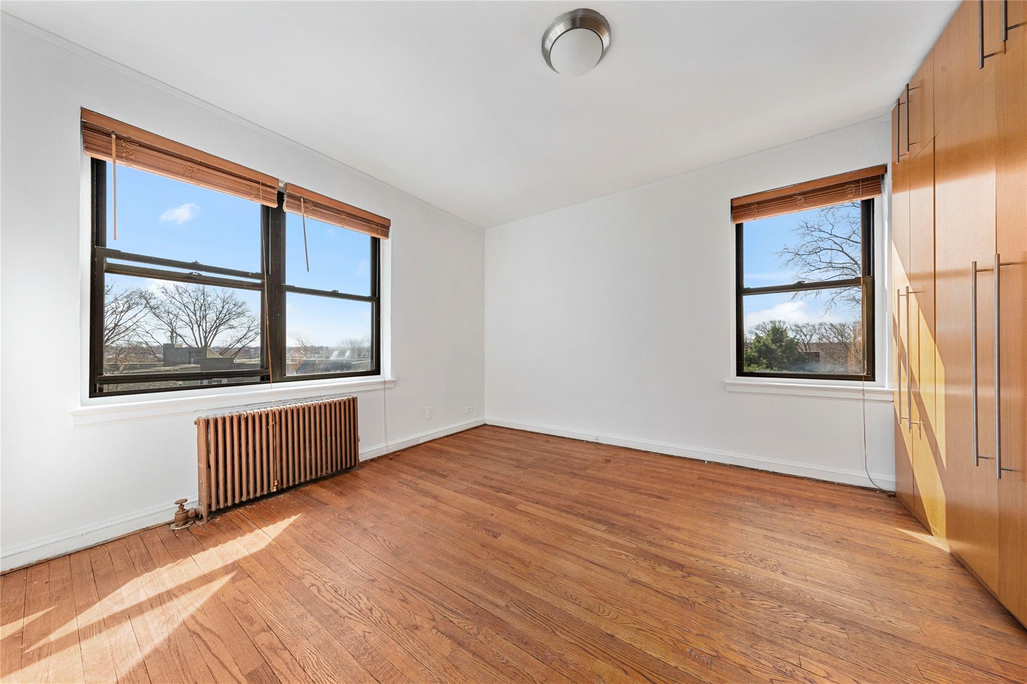 22-20 78th Street, Unit A3 Queens, NY 11370 - Photo 6 of 10 Unfurnished room featuring radiator heating unit, baseboards, and light wood finished floors