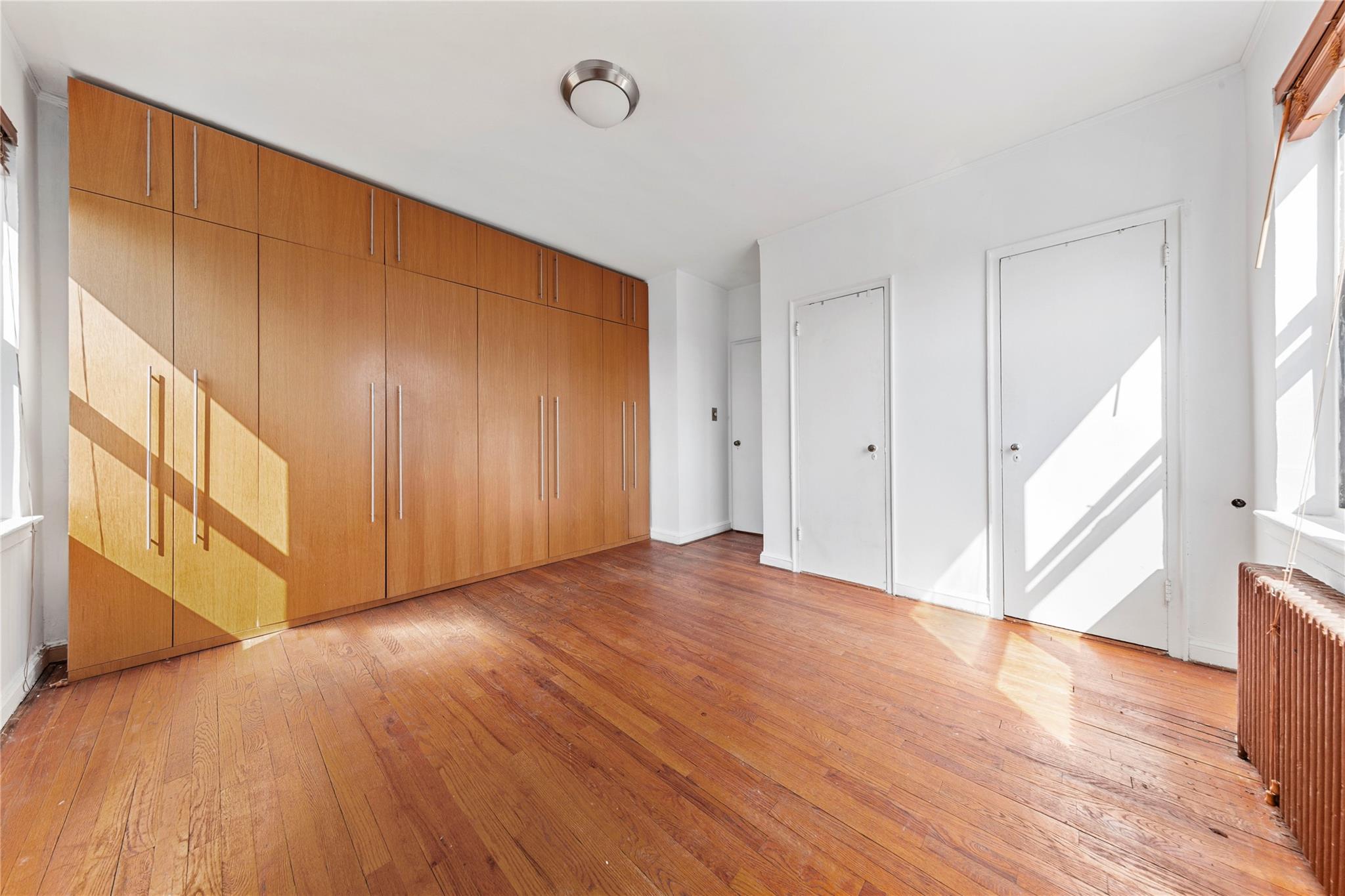 22-20 78th Street, Unit A3 Queens, NY 11370 - Photo 7 of 10 Unfurnished bedroom with radiator heating unit and light wood-style floors
