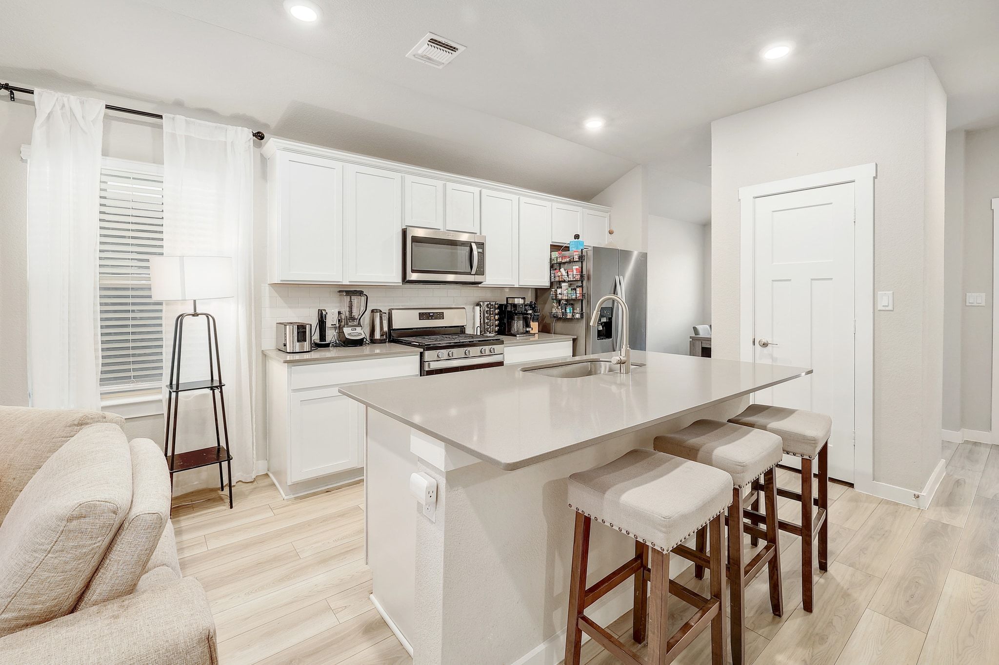 204 Halford Road Georgetown, TX 78633 - Photo 7 of 27 Kitchen featuring a breakfast bar, stainless steel appliances, white cabinetry, backsplash, and light wood-style floors