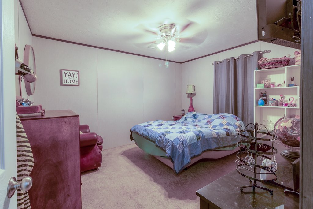 7715 Walnut Tree Lane Plantersville, TX 77363 - Photo 21 of 41 a bedroom with a bed and a chandelier