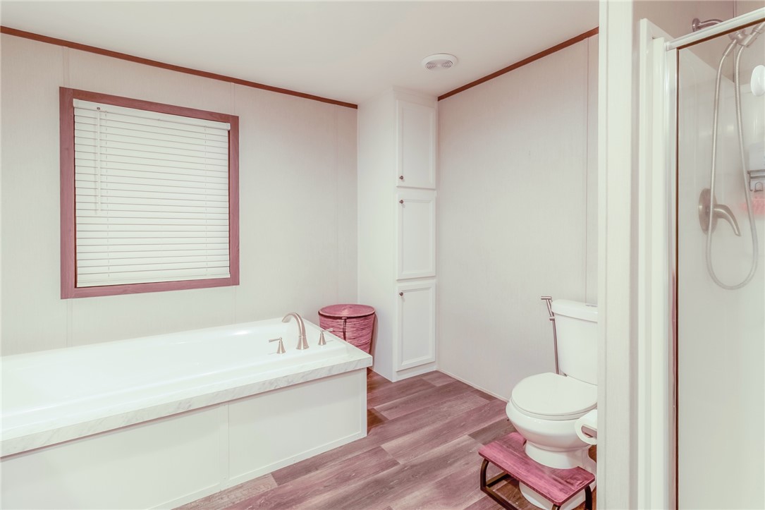 7715 Walnut Tree Lane Plantersville, TX 77363 - Photo 26 of 41 Full bathroom featuring light wood-type flooring, a garden tub, ornamental molding, and a shower stall