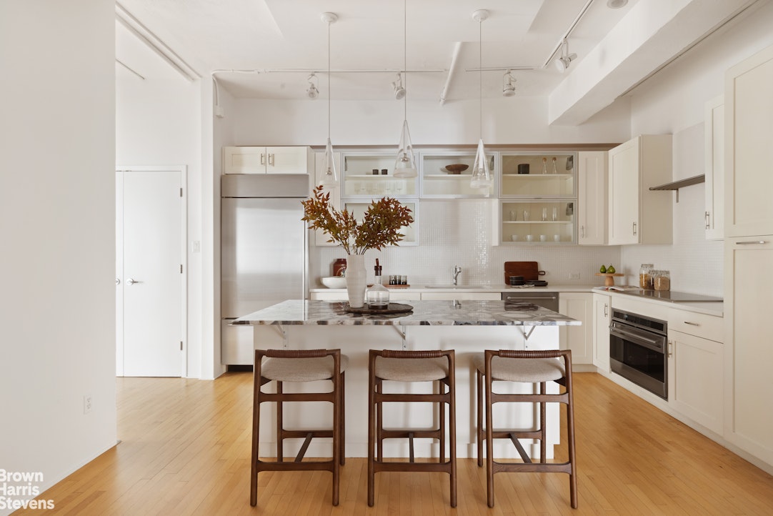 152 Wooster Street, Unit 5B Manhattan, NY 10012 - Photo 5 of 22 a kitchen with kitchen island a stove a table and chairs in it