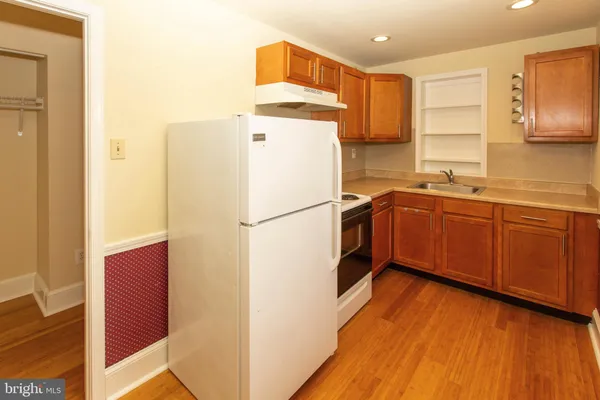 a kitchen with stainless steel appliances granite countertop a refrigerator a sink dishwasher and wooden cabinets with wooden floor