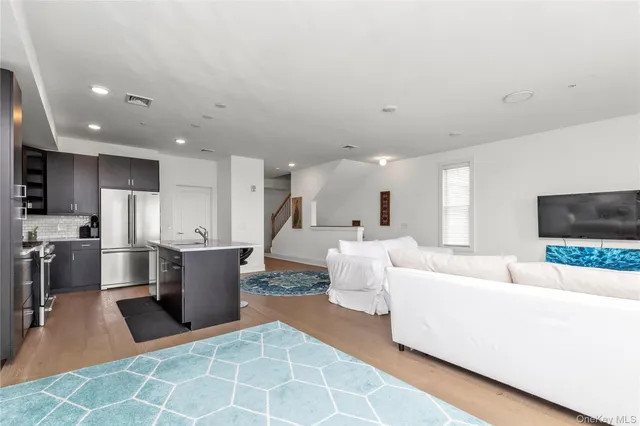 a living room with furniture a flat screen tv and kitchen view
