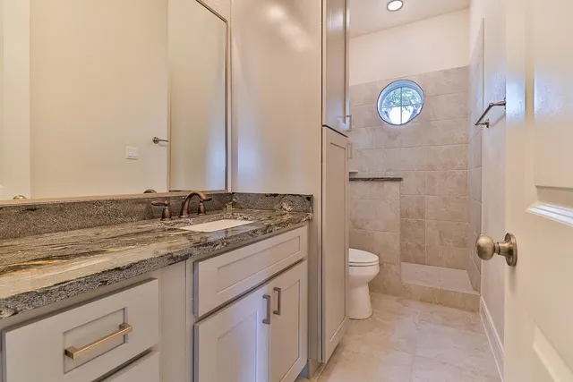 a bathroom with a granite countertop sink and a toilet