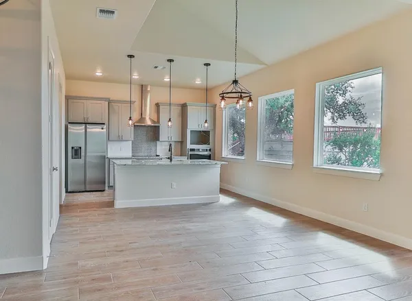 a view of kitchen with stainless steel appliances granite countertop cabinets and a wooden floor