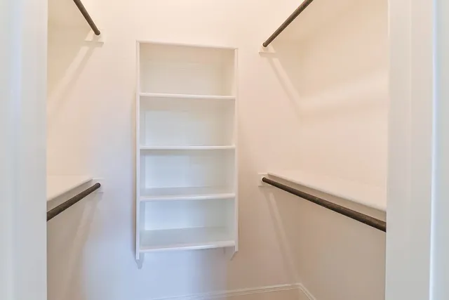 a view of walk in closet with empty racks
