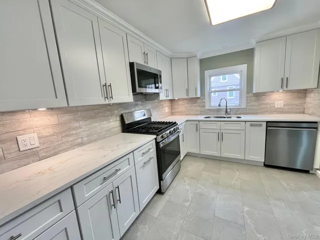 a kitchen with white cabinets stainless steel appliances and sink