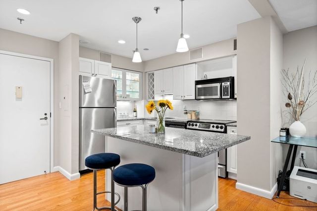 a kitchen with stainless steel appliances granite countertop a refrigerator a stove top oven a sink dishwasher a dining table and chairs with wooden floor