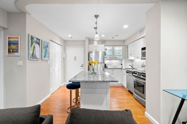 a large kitchen with stainless steel appliances kitchen island a large counter top a stove and a chandelier