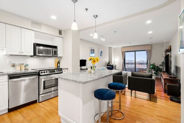 a kitchen with stainless steel appliances granite countertop a stove a sink dishwasher a dining table and chairs with wooden floor