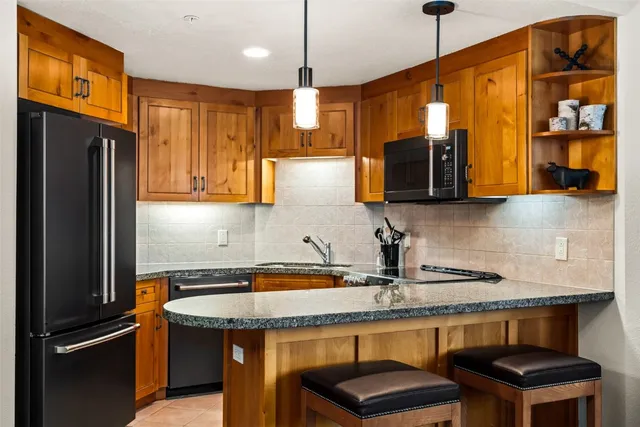 a kitchen with stainless steel appliances granite countertop a refrigerator a sink and wooden cabinets