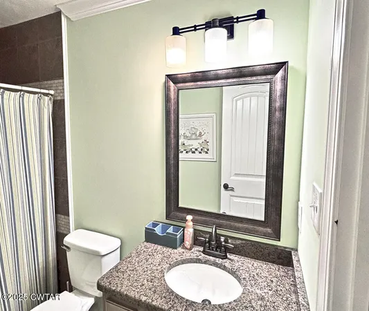 a bathroom with a granite countertop toilet a sink and a mirror