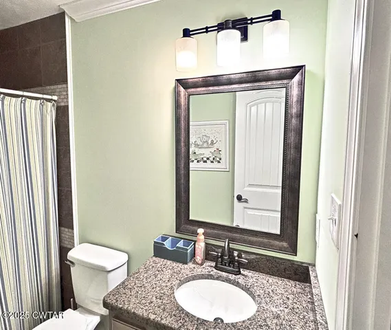 a bathroom with a granite countertop toilet a sink and a mirror