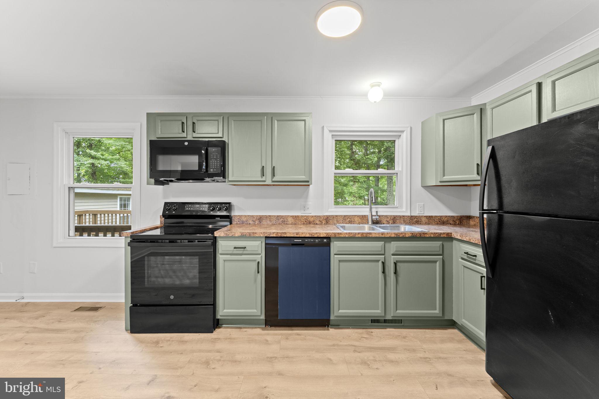 1821 James City Road Reva, VA 22735 - Photo 12 of 44 a kitchen with stainless steel appliances granite countertop a stove a refrigerator and a sink with wooden cabinets