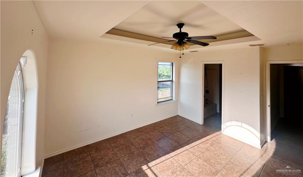311 Teodora Drive Rio Grande City, TX 78582 - Photo 4 of 15 Tiled empty room featuring a tray ceiling and a ceiling fan