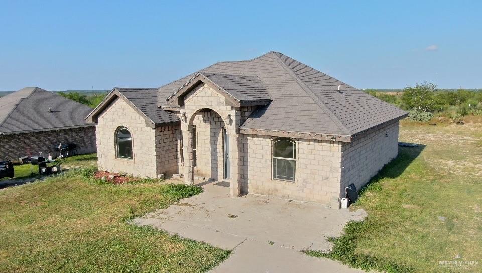 311 Teodora Drive Rio Grande City, TX 78582 - Photo 10 of 15 French country inspired facade featuring a front lawn, stone siding, a shingled roof, and concrete block siding