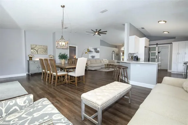 a living room with stainless steel appliances furniture a rug and a kitchen view