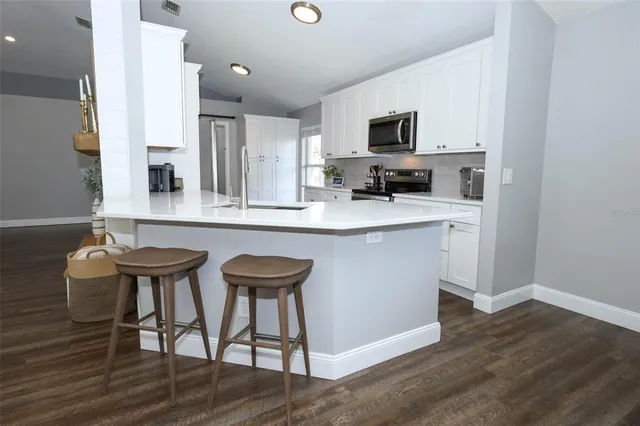 a kitchen with stainless steel appliances a dining table chairs microwave and sink
