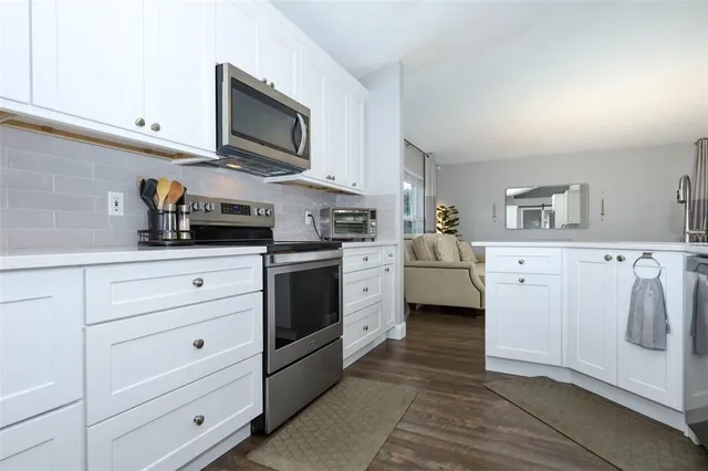 a kitchen with stainless steel appliances white cabinets a sink and a stove