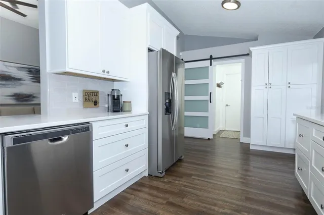 a kitchen with white cabinets and wooden floor