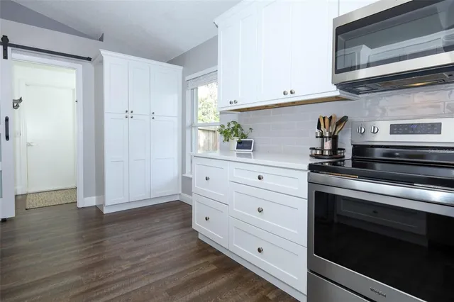 a kitchen with stainless steel appliances white cabinets and a wooden floor