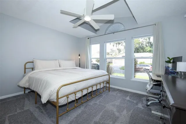 a bedroom with a bed a large window with table and chair