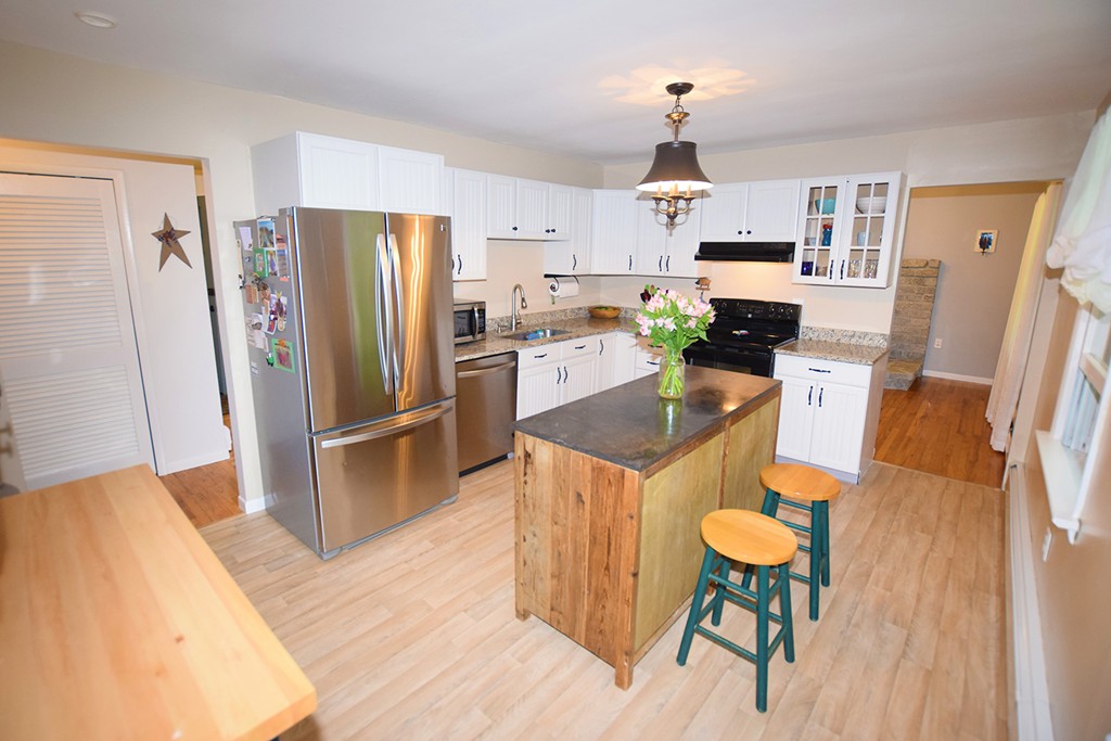 34 Hardwick Road Petersham, MA 01366 - Photo 11 of 24 a kitchen with stainless steel appliances a refrigerator a stove a sink a dining table and chairs with wooden floor