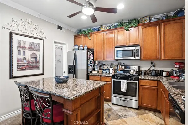 a kitchen with stainless steel appliances granite countertop a stove top oven a sink dishwasher a dining table and chairs with wooden floor