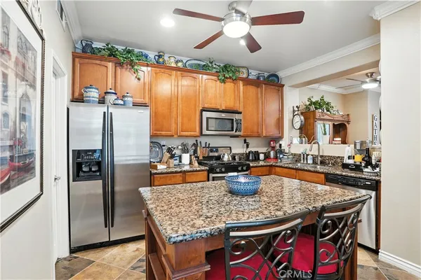 a kitchen with stainless steel appliances granite countertop a stove refrigerator a dining table and chairs with wooden floor