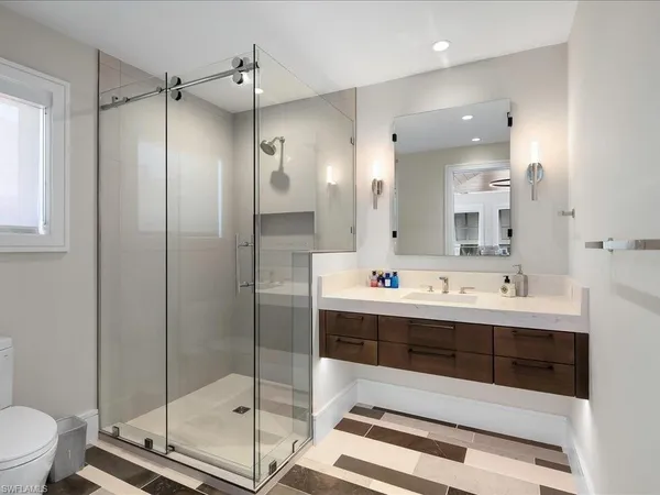 a bathroom with a shower sink mirror and toilet