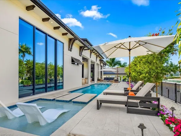 a roof deck with table and chairs under an umbrella with a small yard